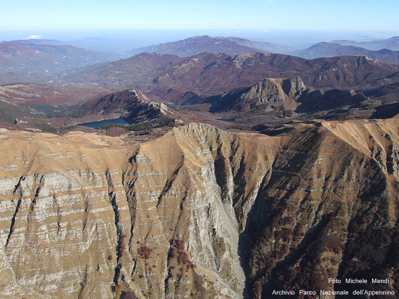 Le ripide pareti del versante sud in primo piano, sullo sfondo l'Appennino Parmense